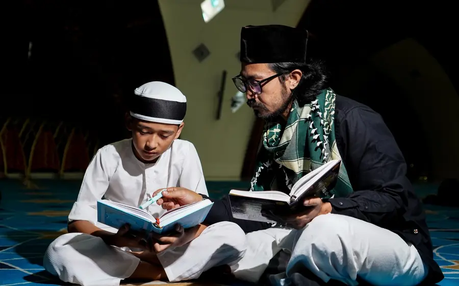 Seorang bapa dan anak lelakinya membaca buku bersama