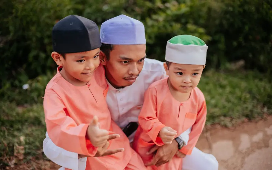 Seorang bapa bersama dua anak lelakinya tersenyum gembira